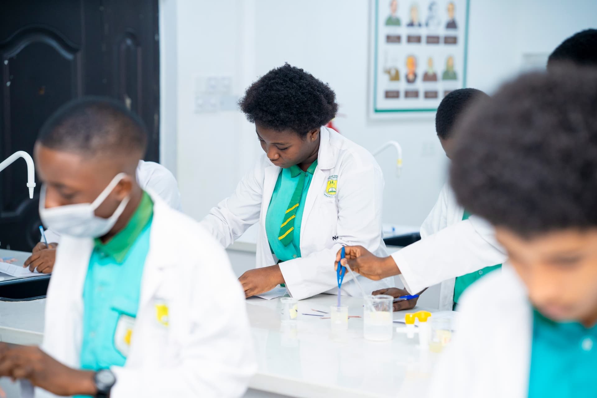 GCSL students in lab coats conducting a chemistry practical