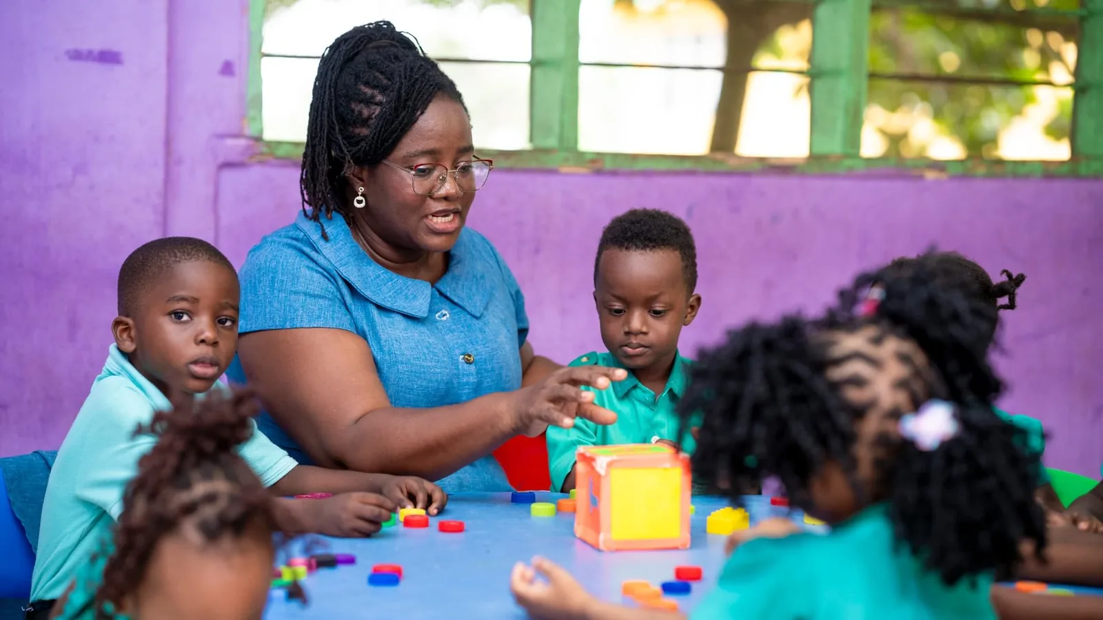 A qualified teacher guiding pre-school pupils