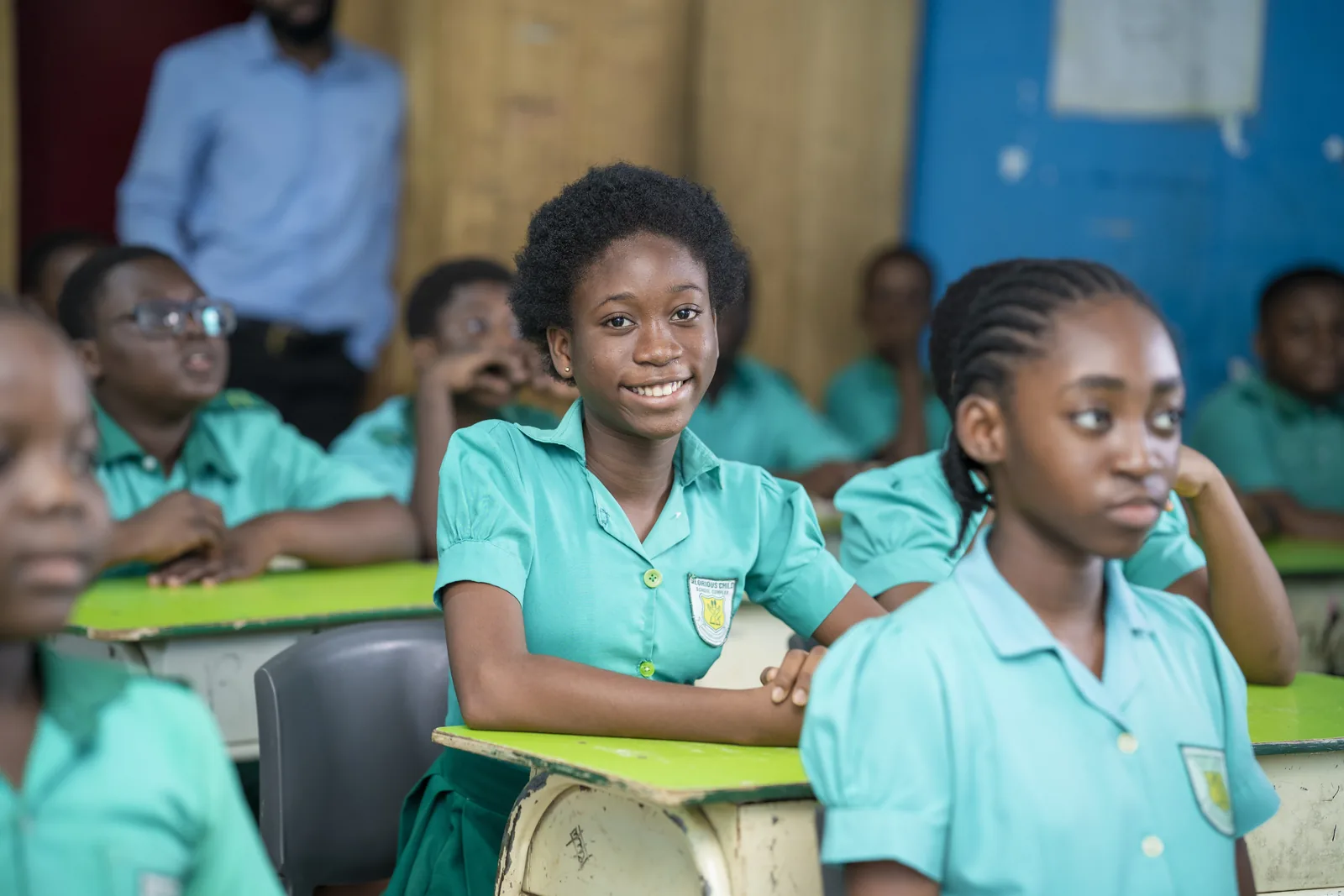 A pupil smiling in a classroom of desks