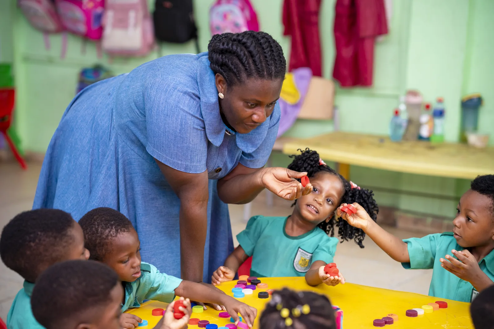 A teacher closely engaging with early-years pupils